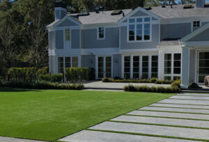 Large home with a manicured artificial lawn and paver walkway