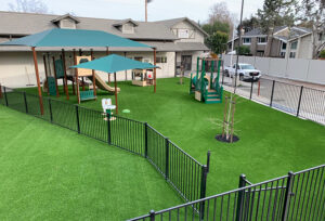 Playground structure on artificial turf inside a fenced yard
